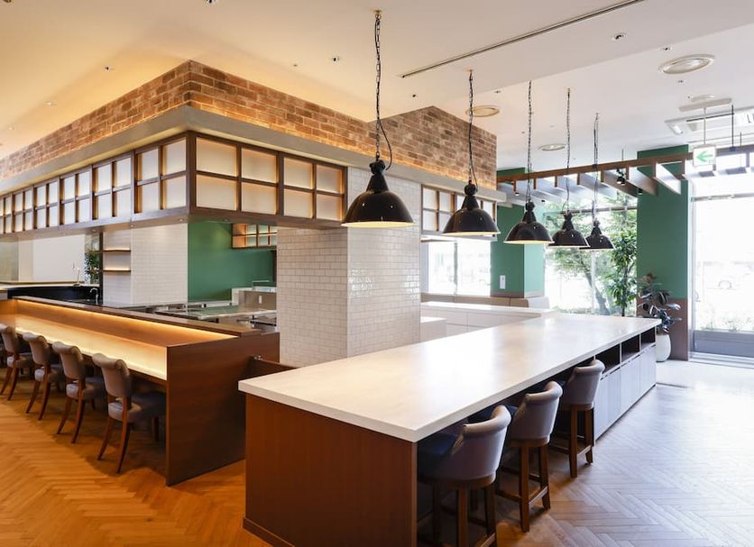 Apa Hotel Sagaeki Minamiguchi restaurant with long counter seating, pendant lights, and herringbone wood flooring in Saga