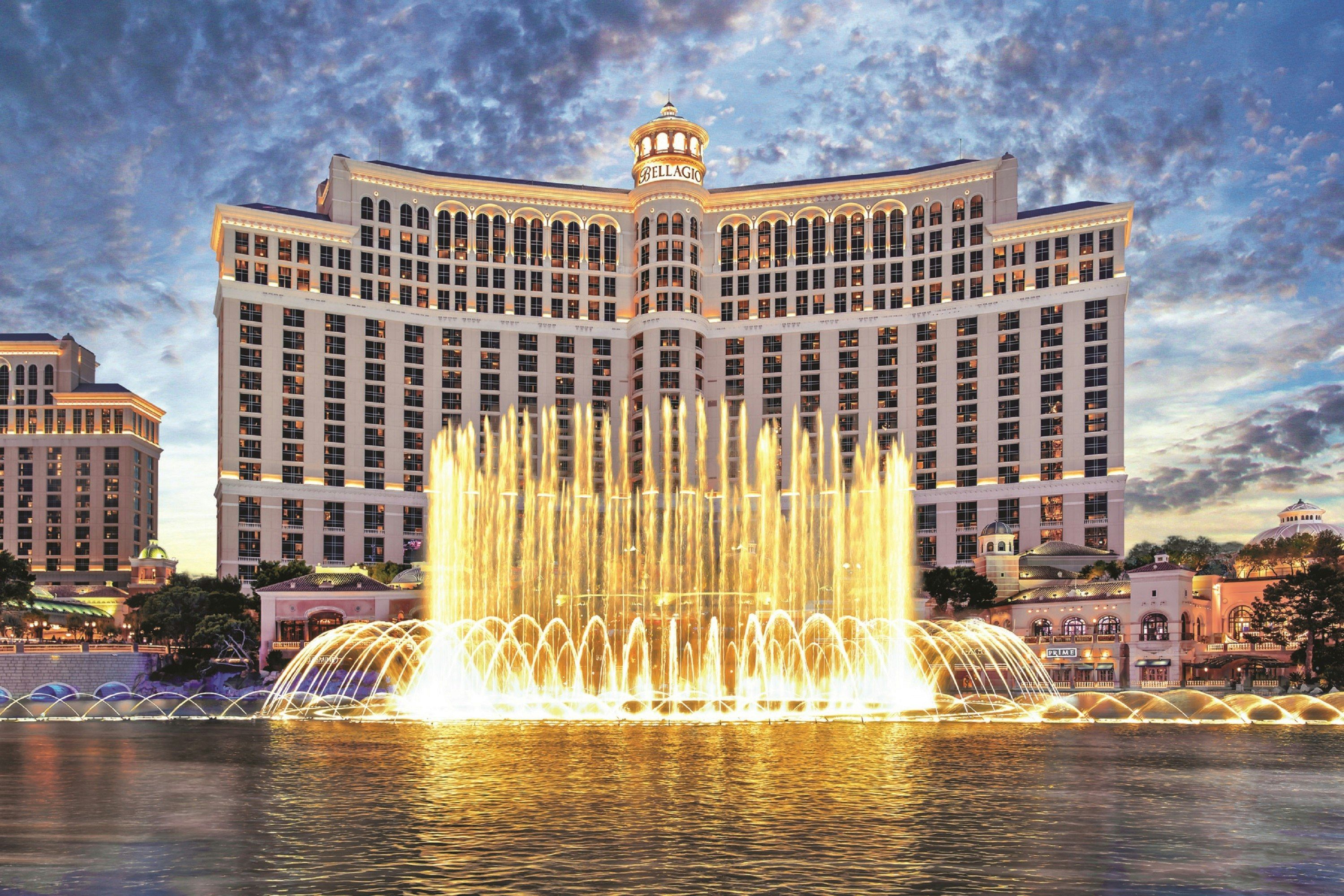 Bellagio Las Vegas with illuminated fountain show in front of the hotel at dusk