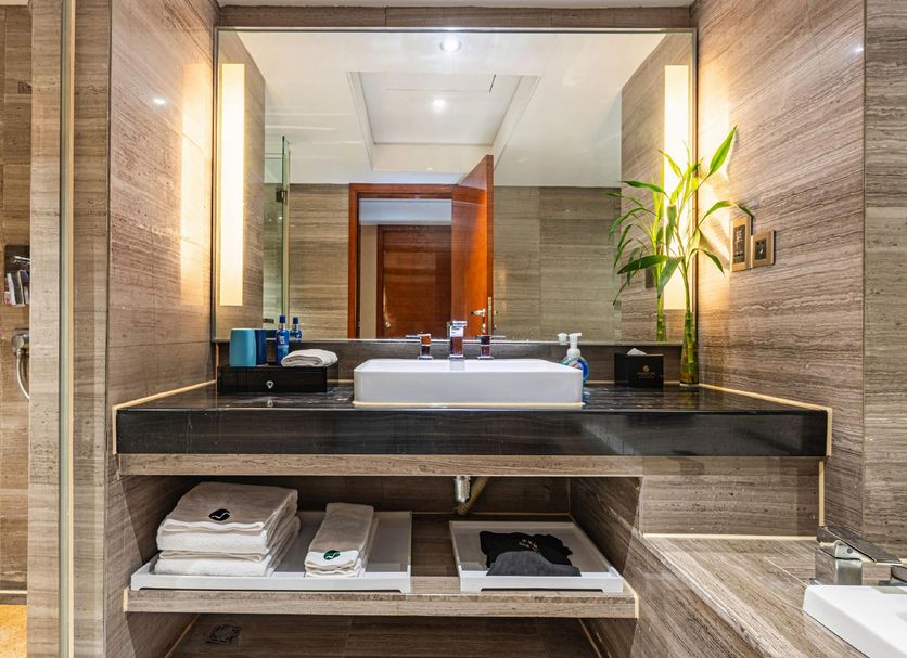 Manhattan Kinlen Hotel Shishi in Quanzhou bathroom vanity with sink, mirror, towels, and toiletries