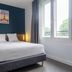 City Résidence Paris Saint-Maurice bedroom with double bed, Paris wall art, and large window in Saint-Maurice