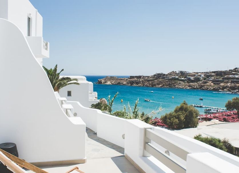 Super Paradise Hotel in Platis Gialos with white terrace and views of turquoise sea and rocky coastline
