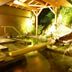 Kameya Ean in Izu features a serene hot spring bath with wooden beams and rock landscaping.