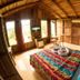 Arenal Bungalows in La Fortuna: wood bungalow room with colorful bedspread, balcony doors and jungle view