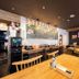 Apa Hotel Koriyama Ekimae restaurant with wooden tables, chairs, and a wall-mounted TV in Kōriyama