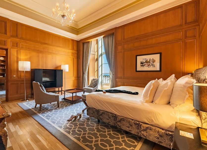 Pousada de Lisboa luxury suite with wood-paneled walls, king bed, seating area and city view in Lisbon