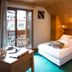 Chalet Hotel Régina in Les Gets: cozy wood-paneled guest room with double bed, balcony doors, and twin bed