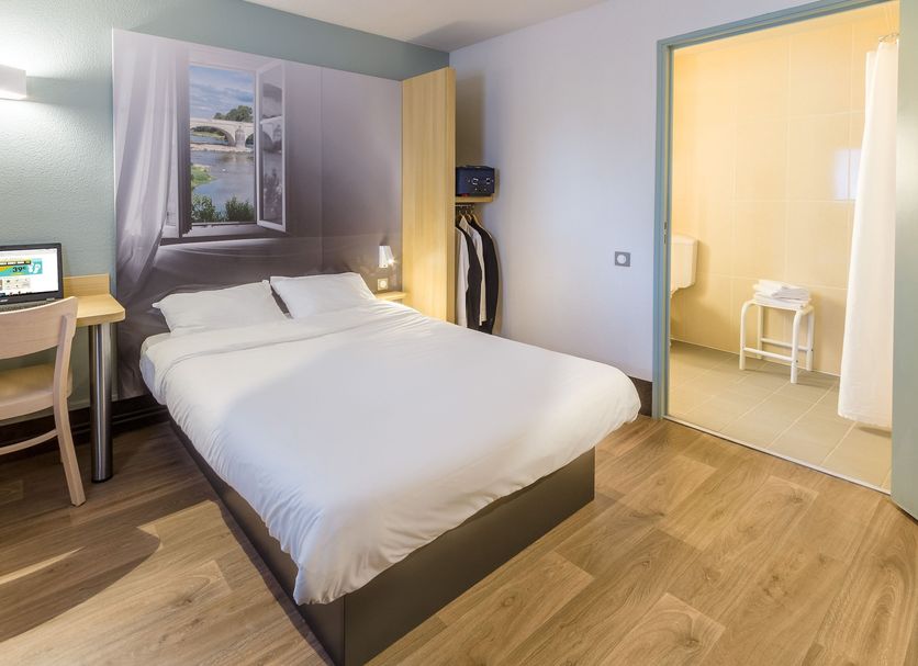 B&B HOTEL Paris Nord Aulnay-sous-Bois room with double bed, desk, chair and open bathroom door in Aulnay-sous-Bois