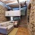 La Freixera in Solsona: stone-walled interior with sofa, stairs and mezzanine walkway