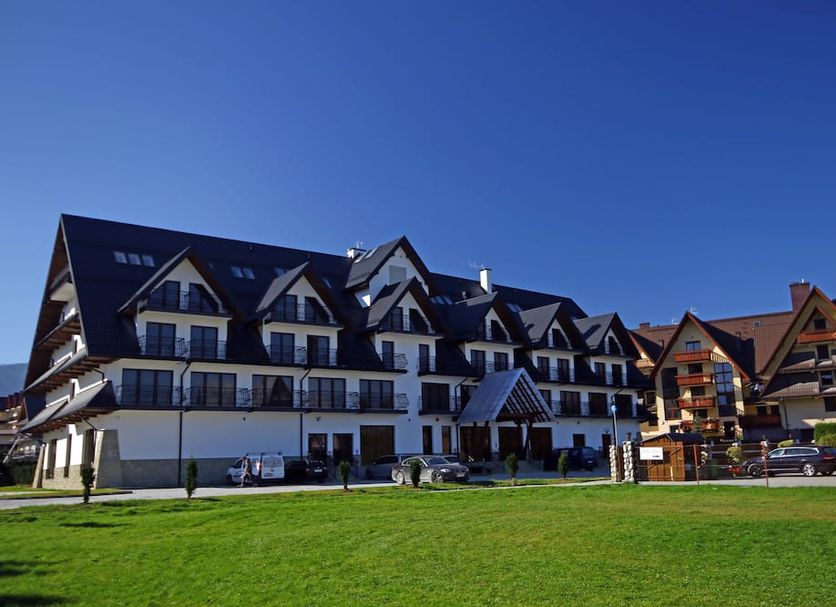 Hotel Paryski Art & Business in Zakopane, mountain-style hotel exterior with green lawn and clear blue sky