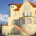 Gästehaus Seewarte in Flensburg, pale yellow hotel with red roof and curved staircase