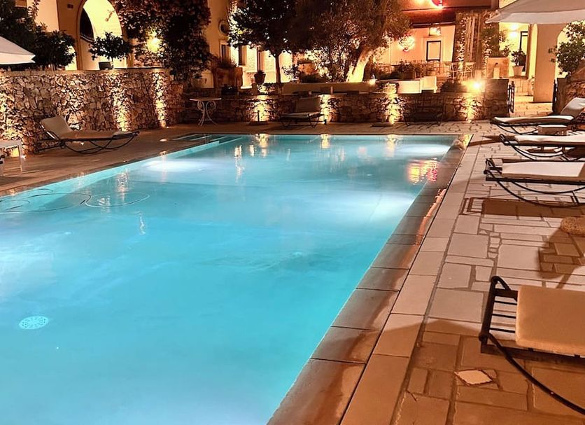 Masseria Le Mandorle, Ugento: illuminated outdoor pool with lounge chairs and stone walls