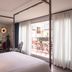 Mom'Art Hotel Paris bedroom with four-poster bed, red balcony chairs and city view