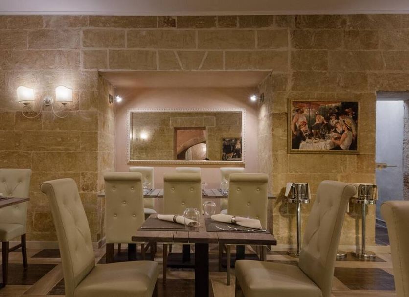 Le Club Boutique Hotel in Lecce: elegant restaurant with tufted chairs, set tables and stone walls