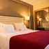 Hotel Miracorgo in Vila Real guest room with king bed, red throw, wall lamps, and mirror