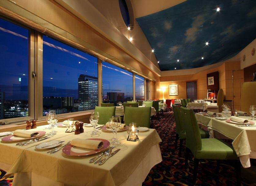 Hotel Nikko Tsukuba in Tsukuba dining room with city view at dusk and set tables