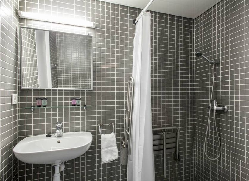 Residencia Universitaria Resa Roberto De Nobili bathroom with sink, mirror, shower and gray tiled walls in Sant Cugat del Vallès