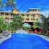 Hotel Los Ranchos in Jacó with tropical pool, lounge chairs, palm trees and colorful buildings