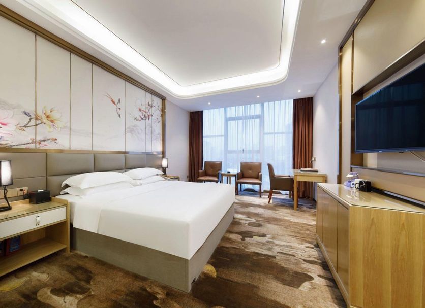 Fulai Garden Hotel in Shenzhen guest room with king bed, work desk, chairs, and large window