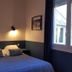 Les Lauriers, Saint-Tropez: cozy double room with blue bedspread, wall sconces, and window view