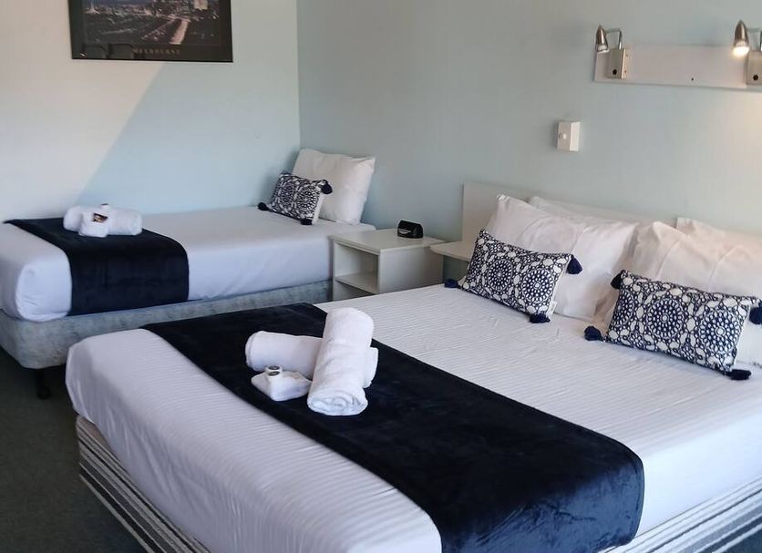 Birch Motel Tocumwal room with two beds, navy throws, patterned pillows, and wall-mounted lights in Tocumwal