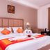 Plaza Hotels Trichy room with king bed, orange accents, armchair, bedside lamp and curtain