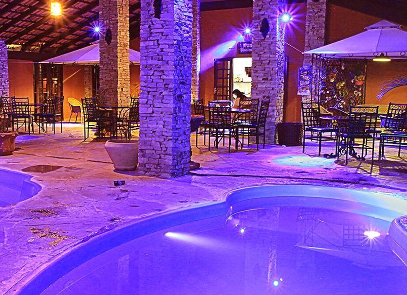 Pousada Villa Das Pedras in Pirenópolis with lit outdoor pool and stone patio seating