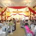 Mawlamyine Strand Hotel in Mawlamyine ballroom with banquet tables and stage decorated in red and gold drapes