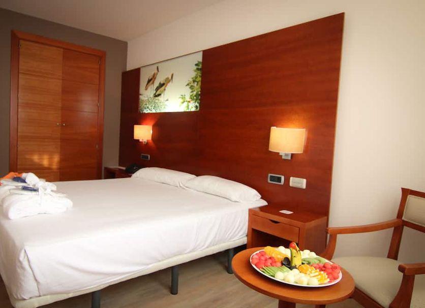 Hotel Balneario Valle del Jerte guest room in Valdastillas with double bed, bedside lamps and fruit tray