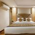 Hotel Waves, New Delhi guest room with king bed, wood flooring, and lounge chair
