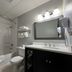 Le Voyageur Inn Mattawa bathroom with tub-shower, sink vanity, toilet and wall-mounted TV