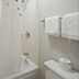 Red Roof Inn Greensboro Airport bathroom with shower-tub combo, toilet, towels and grab bar in Greensboro