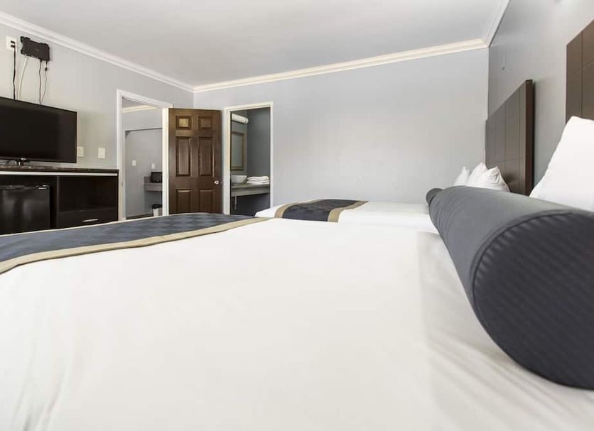 Hollywood Palms Inns & Suites guest room in Los Angeles with two beds, TV, mini fridge and open bathroom door