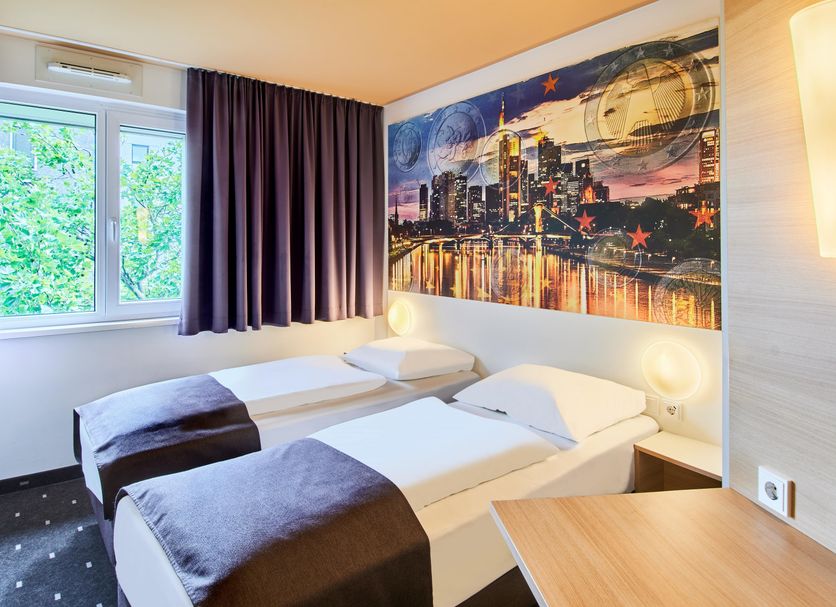 B&B Hotel Frankfurt City-Ost room with two single beds, window, and Frankfurt skyline wall art
