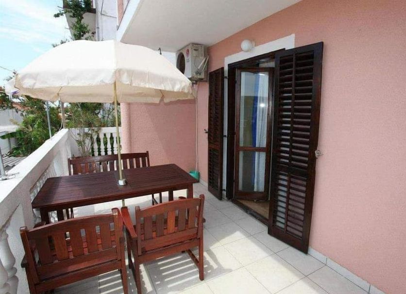 Apartments Alissa in Hvar balcony with table, chairs, and umbrella beside open shutters