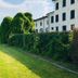 Hotel Villa Policreti in Aviano with manicured lawn, ivy-covered hedge, and white villa exterior