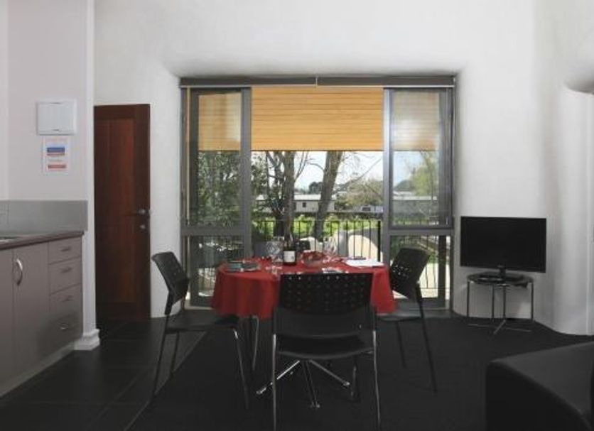 Bon Marie B&B in Hamilton dining area with table, chairs, TV, and balcony doors to greenery