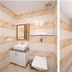 Hotel Golden Inn Chandigarh bathroom with striped tile walls, sink vanity, mirror, shower and toilet