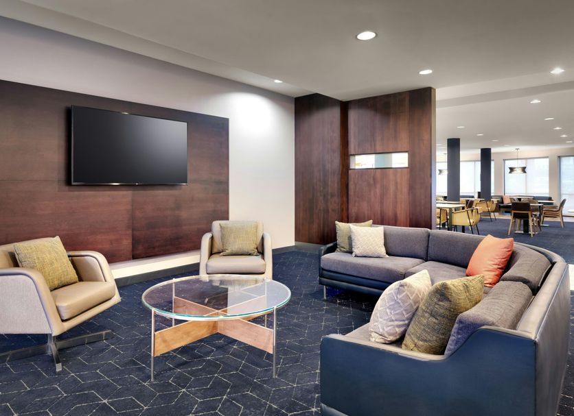 Courtyard by Marriott Johnson City lounge with sofas, armchairs, wall-mounted TV and glass coffee table