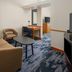 Fairfield Inn & Suites by Marriott Santa Maria guest room with sofa, desk, TV and blue patterned carpet
