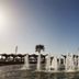 Sun City Hotel in Tel Aviv with a waterfront fountain display and palm trees under a clear sky