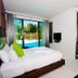 Chalay Monta Hua Hin guest room with bed, pool view through sliding glass doors, and wall-mounted TV