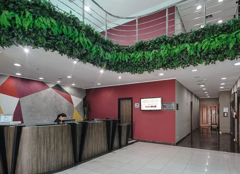 Hotel The Premium lobby in Osasco with reception desk, tiled floor, and leafy ceiling decor