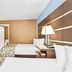 Baymont by Wyndham Forest City guest room with two beds, TV, desk, and beige patterned carpet