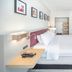 Hilton Garden Inn Clifton Park guest room with king bed, wall art, TV, and open closet