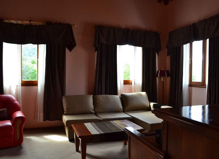 Valle Frio Ushuaia in Ushuaia living room with sofa, red armchair, and large windows with curtains