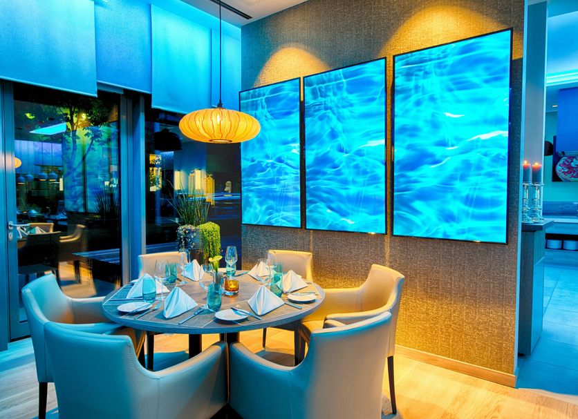 Leonardo Hotel Munich City South dining area with round table and blue-lit wall panels in Munich