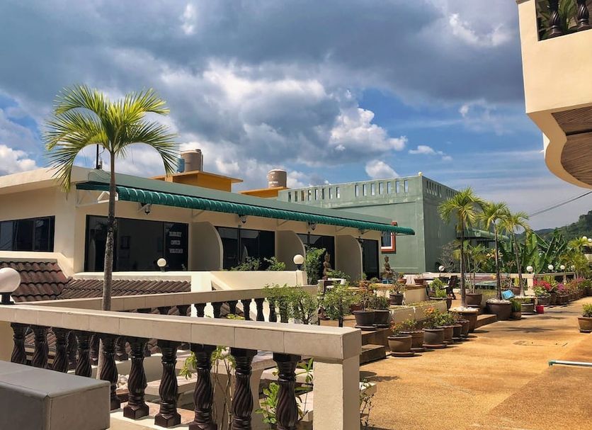 Blue Sky Residence Patong outdoor courtyard with palm trees, balcony railings and cloudy sky