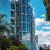 Hotel Verona Tower in Divinópolis with glass tower exterior framed by lush trees under a blue sky