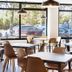 B&B Hotel Figueres breakfast area with tables, chairs and large windows overlooking parked cars
