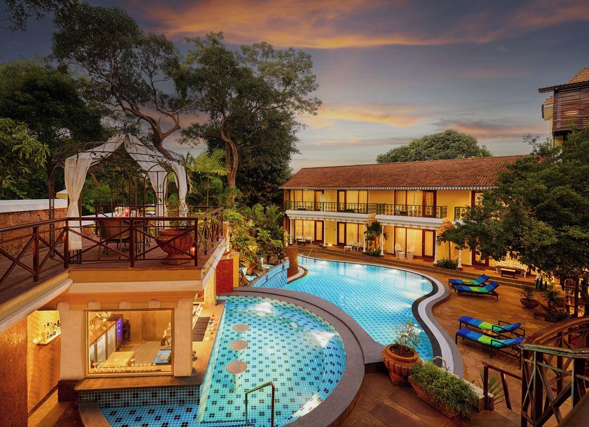 Storii By ITC Hotels, Shanti Morada Goa in Saligao: lit outdoor pool and courtyard at sunset